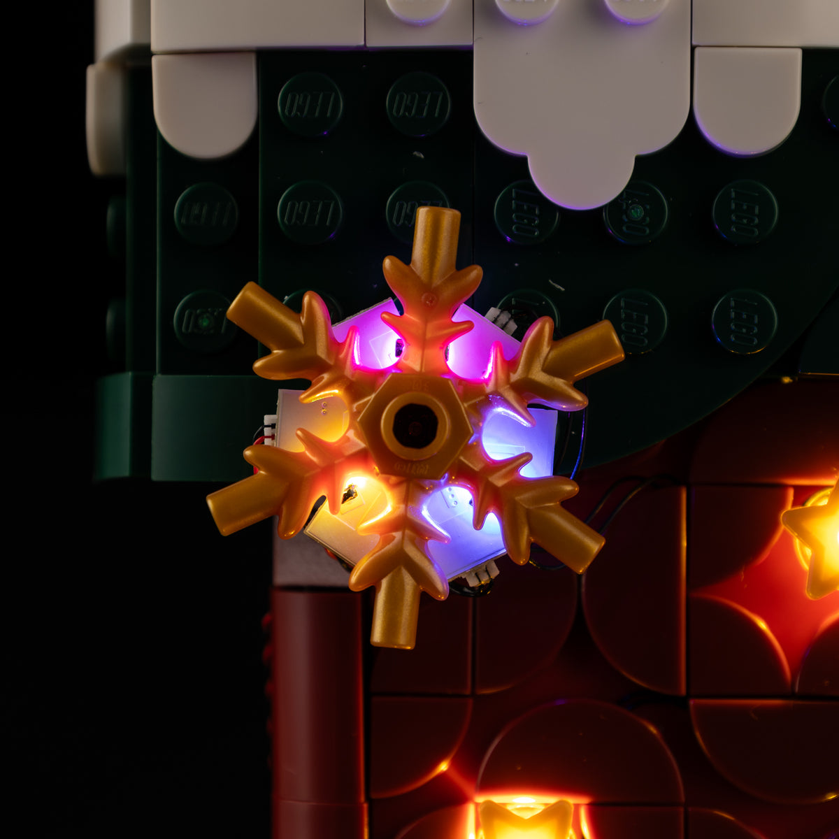 Real multicolor LEDs around the gold snowflake on the green cuff of LEGO® Christmas Stocking 40958.