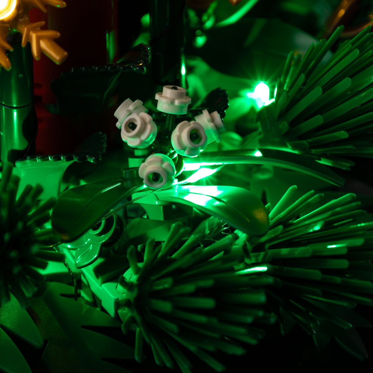 Actual white blossom pieces and foliage catching the green kit light around LEGO® Christmas Table Decoration 40743.