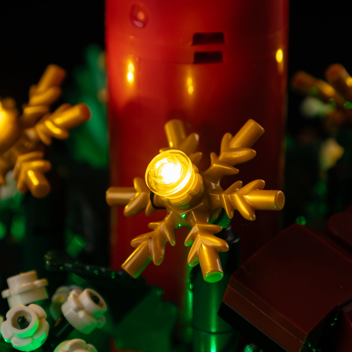 Actual warm LED light in the gold snowflake ornament beside the LEGO® red candle.