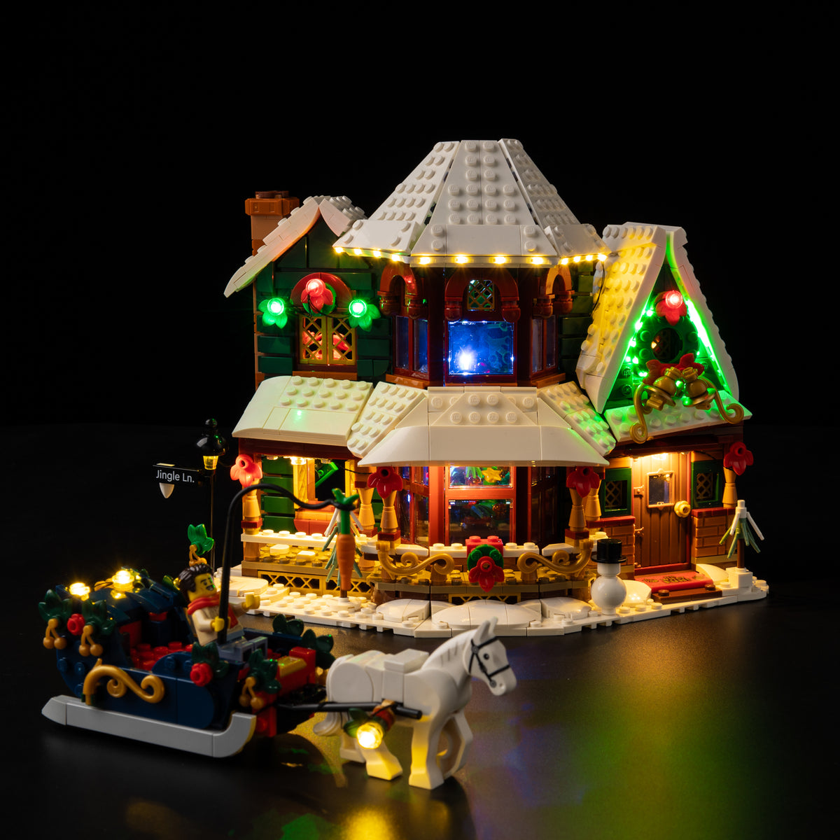 LEGO® Holiday House 11387 with warm porch and roof lighting, red and green festive details and the illuminated horse-drawn sleigh.