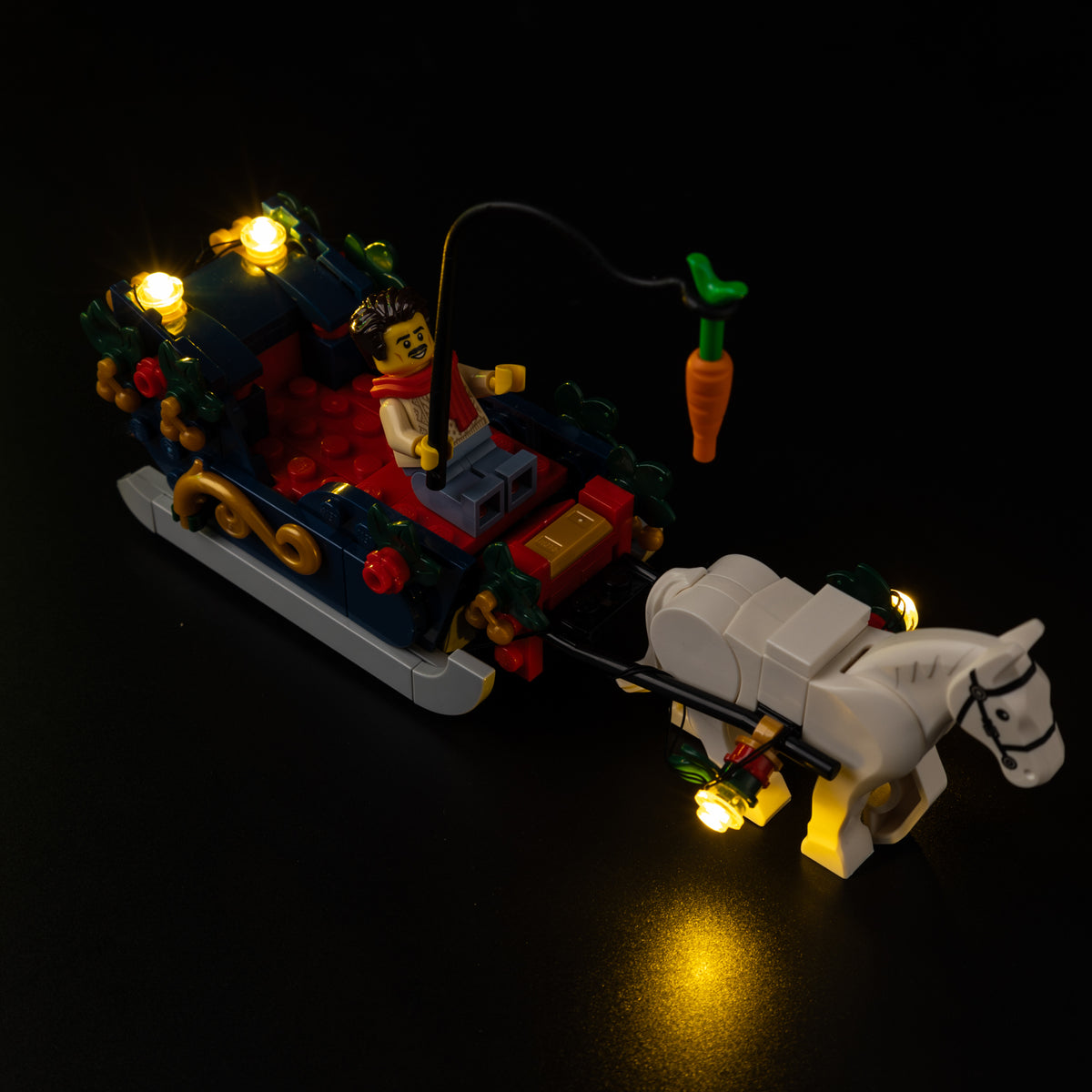 Illuminated lanterns on the LEGO Holiday House horse-drawn sleigh beside the white horse.