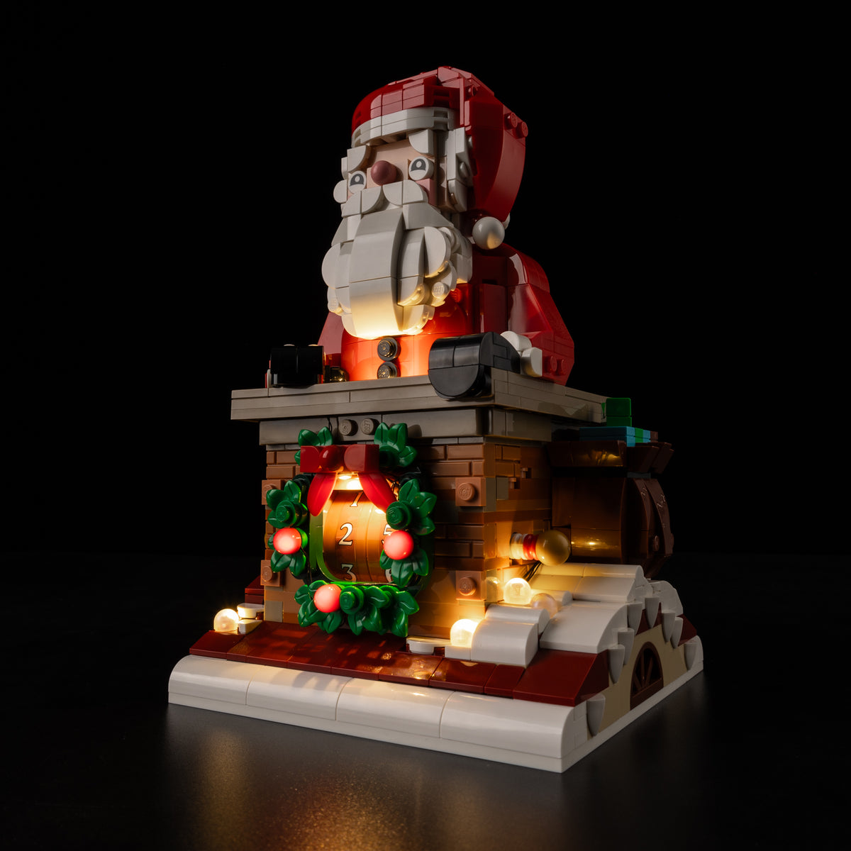 Side view of the actual illuminated Santa, brick chimney, wreath and snowy base in LEGO® Santa’s Holiday Countdown 40874.