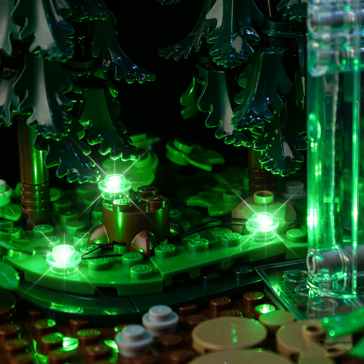 Real green kit lights on the brick-built woodland floor among the LEGO trees.