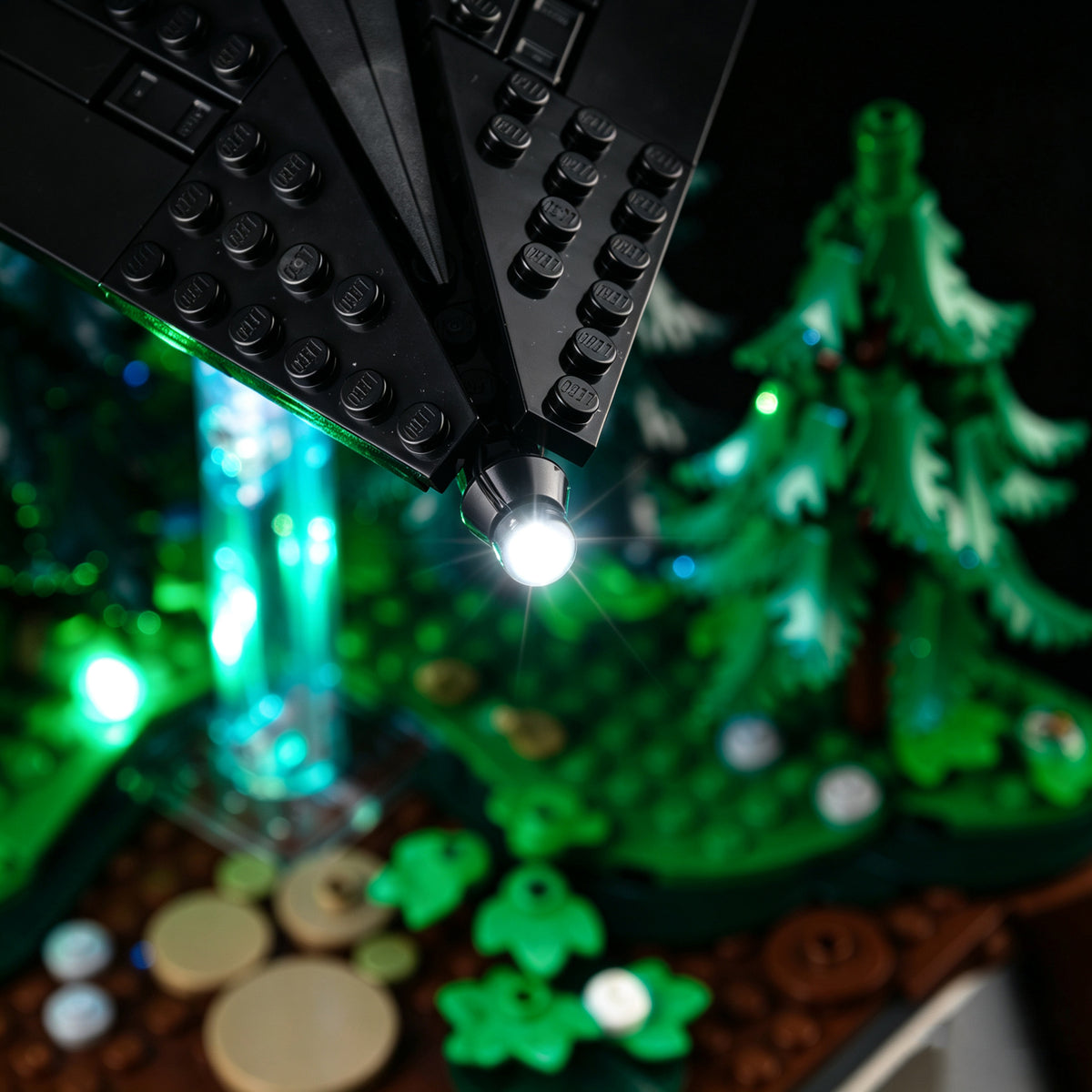 Close-up of a white UFO edge LED above green-lit LEGO woodland.