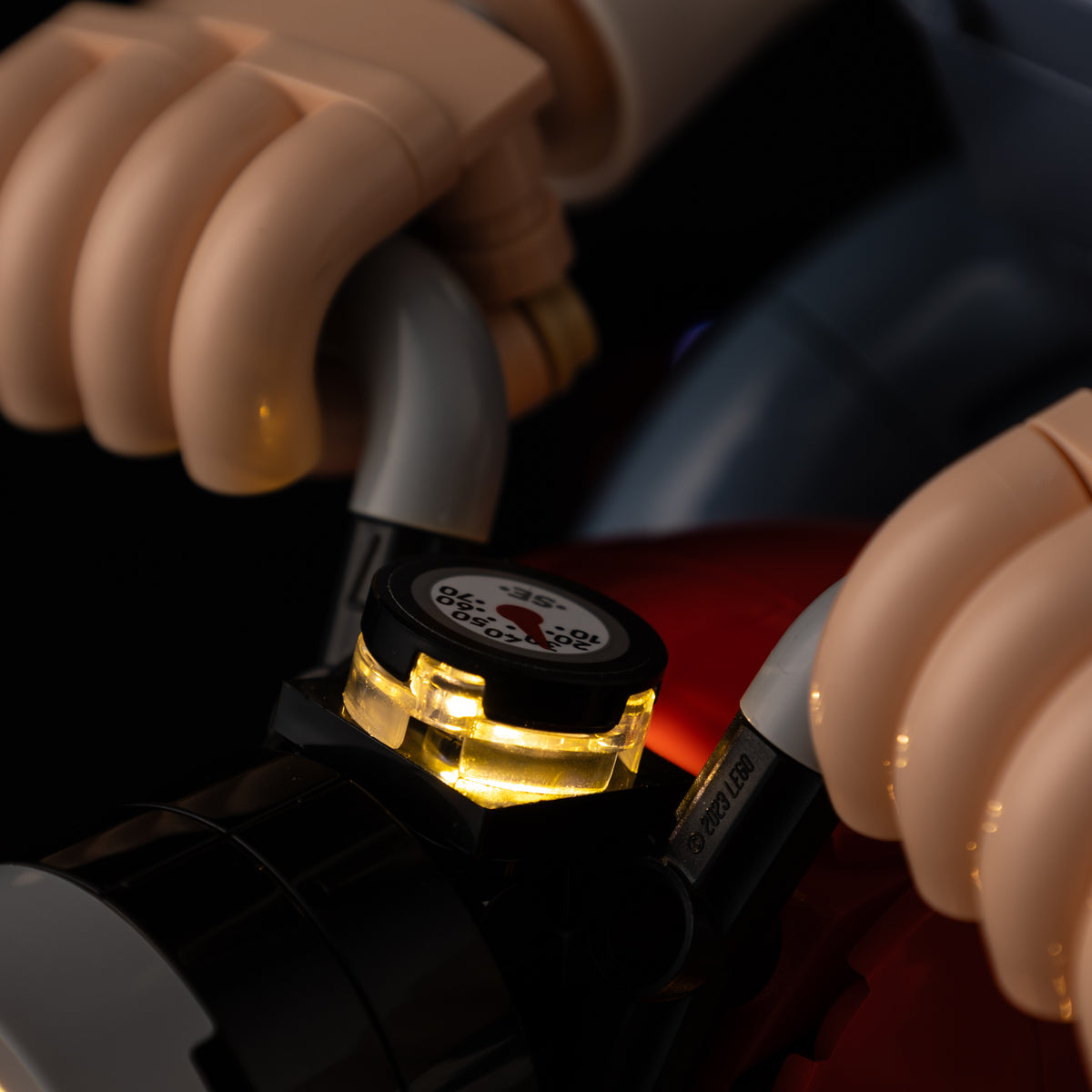 Real warm light beneath the dashboard gauge between Wallace’s hands on the LEGO® motorbike.