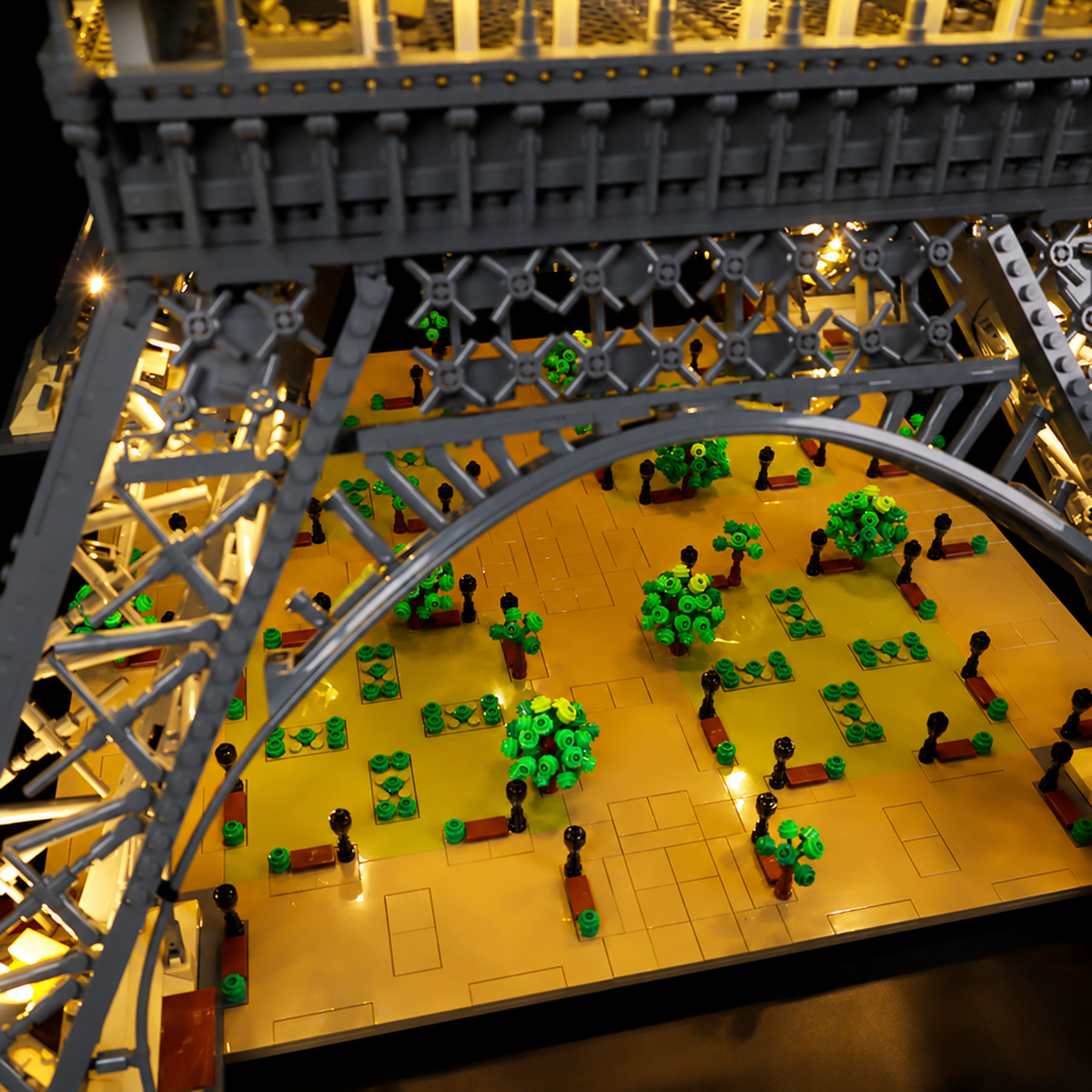 Warm Classic kit lighting over the landscaped esplanade and arches of LEGO Eiffel Tower 10307.