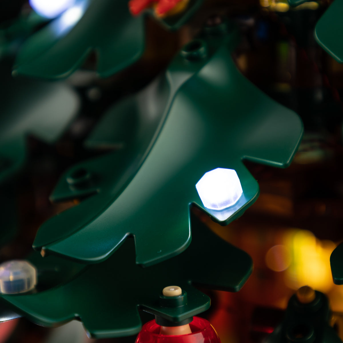 Cool white light on a green branch above a red bauble in the LEGO Family Christmas Tree 41843
