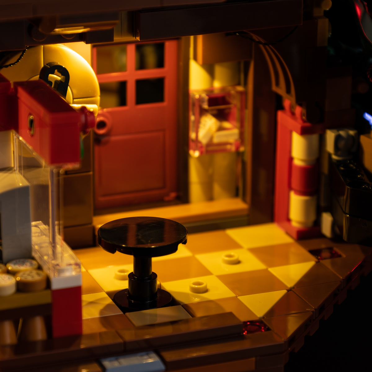 Warm light across the tiled floor beside a black stool in the LEGO Family Christmas Tree 41843